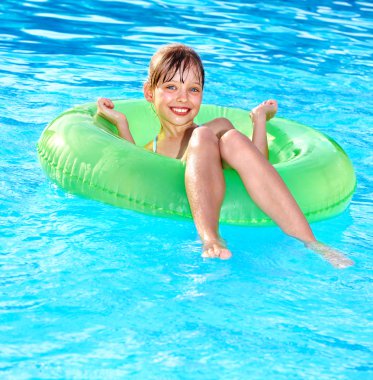 Child sitting on inflatable ring in swimming pool. clipart