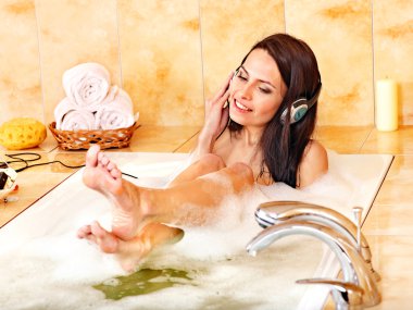 Woman listening to music in bubble bath. clipart