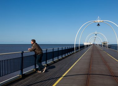 Senior man looking out over beach at Southport clipart