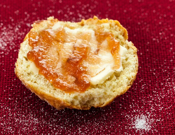 Half scone with butter and jam on red tablecloth — Stock Photo, Image
