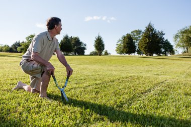 Senior man cutting grass with shears clipart