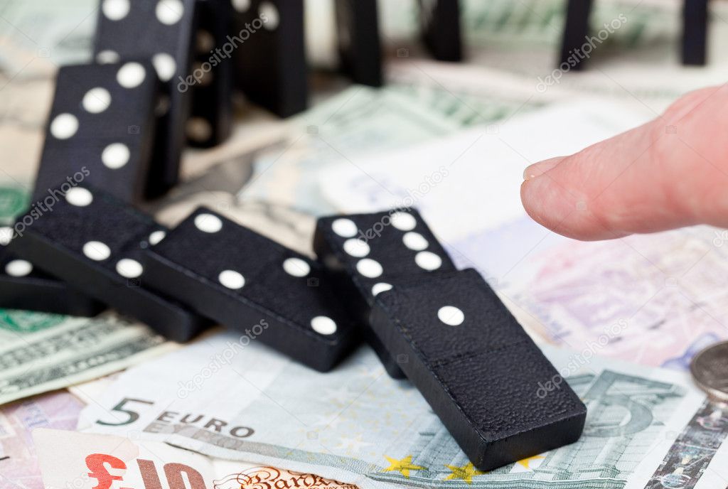Finger on dominoes on bank notes
