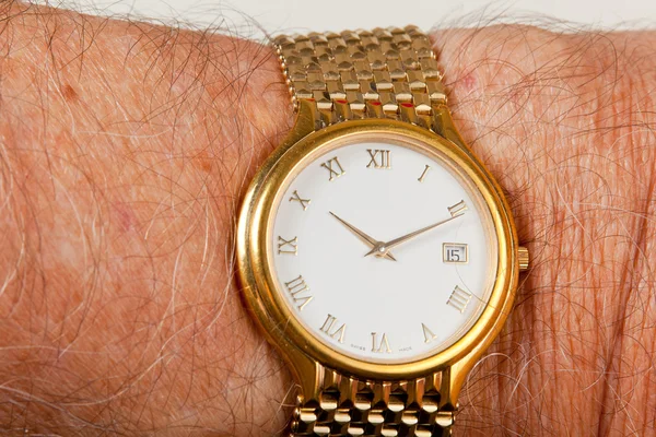 Relógio de ouro com rosto branco no pulso peludo — Fotografia de Stock