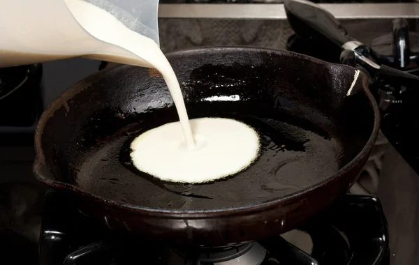 Pouring pancake mix into frying pan — Stock Photo, Image