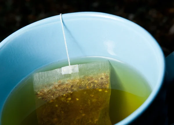 Zelený čaj pivovarnictví v horké vodě v modré cup — Stock fotografie