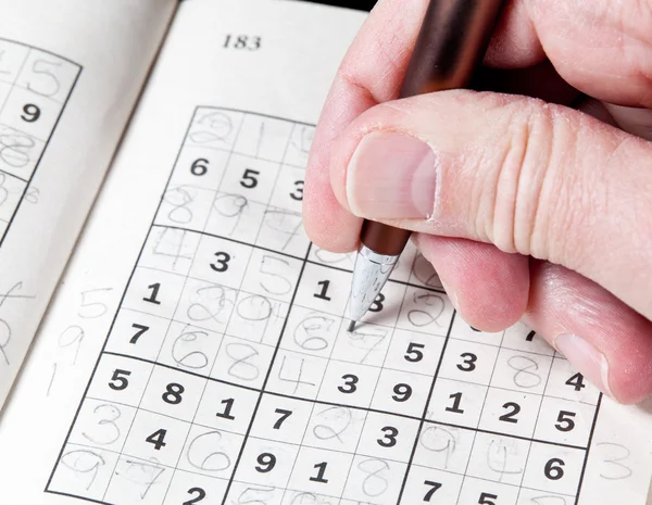 Man hand holding pencil on sudoku puzzle — Stock Photo, Image
