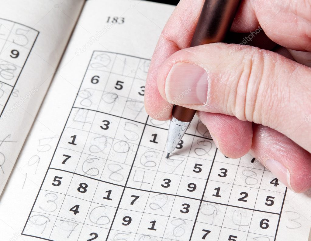 Man hand holding pencil on sudoku puzzle