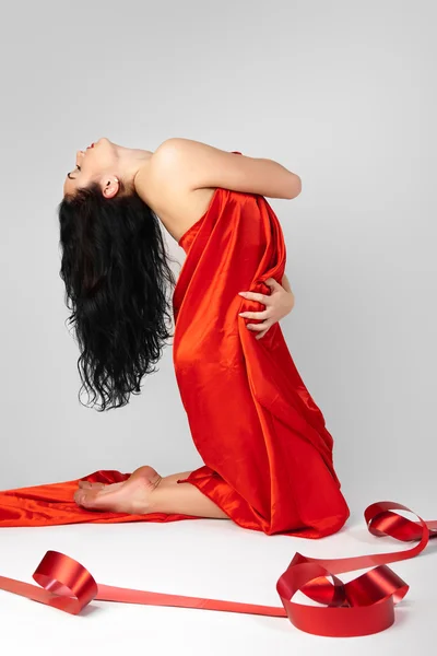 Schöne junge Frau ist mit rotem Tuch bedeckt. — Stockfoto