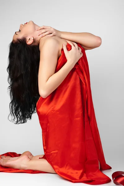 Mooie jonge vrouw is bedekt met rode doek. — Stockfoto