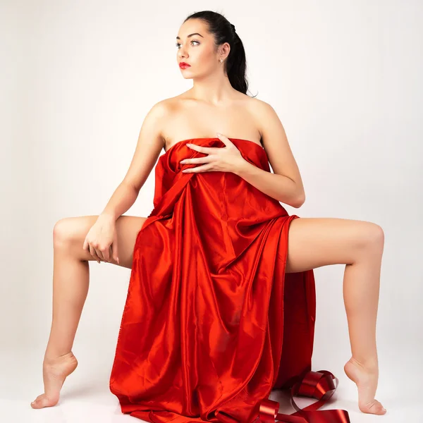 Vacker ung kvinna som är täckt med rött tyg. — Stockfoto