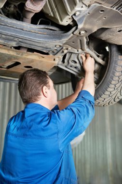 Auto mechanic at car suspension repair work clipart