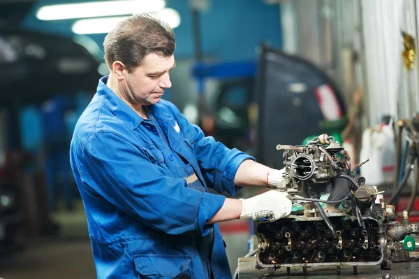 Auto mechanic at repair work with engine — Stock Photo, Image
