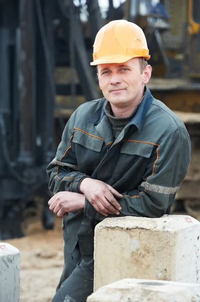 Construtor em roupas de trabalho sujas no local de construção — Fotografia de Stock