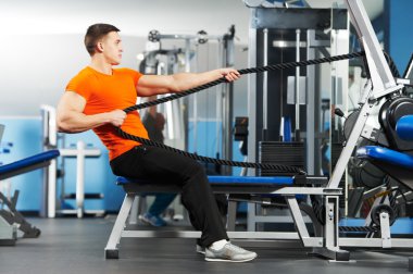 Bodybuilder man doing exercises in fitness club clipart