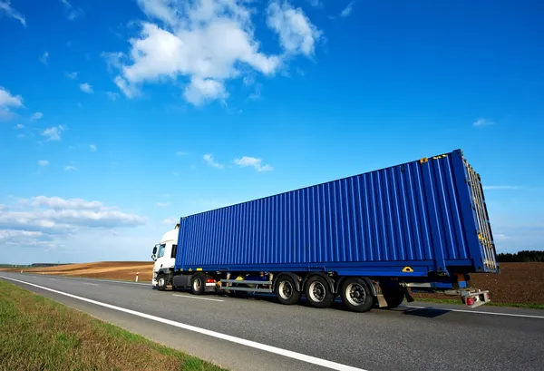 Rode vrachtwagen met grijze aanhangwagen over blauwe hemel — Stockfoto