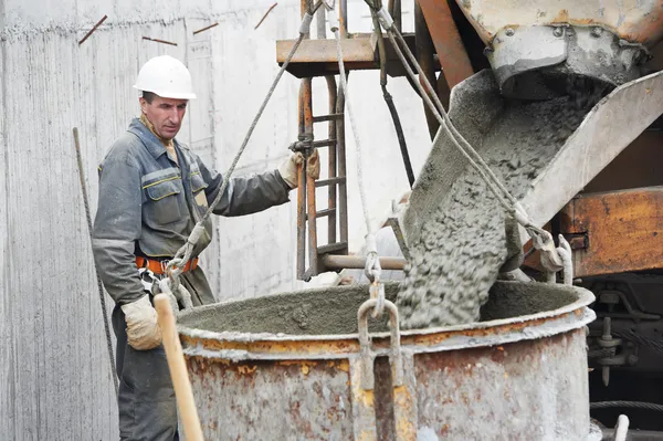 Constructor trabajador vertiendo hormigón en barril — Foto de Stock