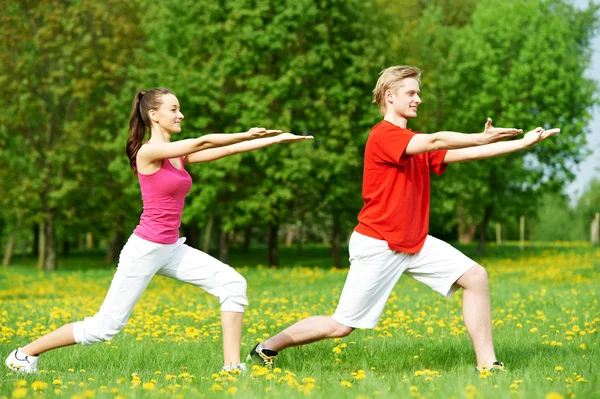Młody mężczyzna i kobieta robi ćwiczenia rozciągające — Zdjęcie stockowe