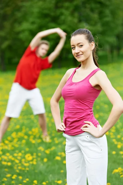 Ung man och kvinna göra stretchingövningar — Stockfoto