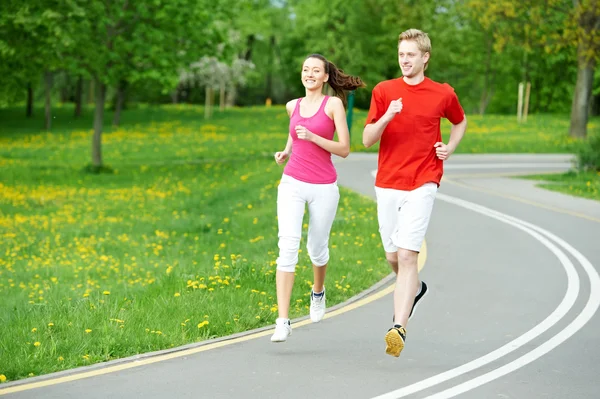 Young man and woman jogging outdoors — Stock Photo, Image
