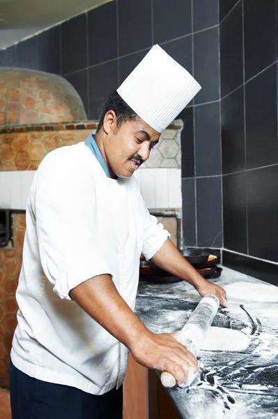 Um chef padeiro em uniforme branco malabarismo com pastelaria para pizza na cozinha — Fotografia de Stock