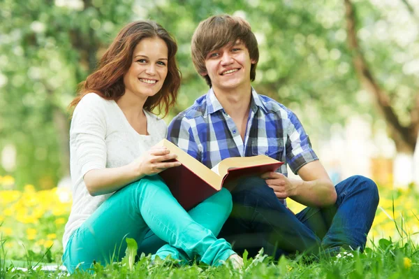 Dos jóvenes estudiantes sonrientes al aire libre con libro —  Fotos de Stock