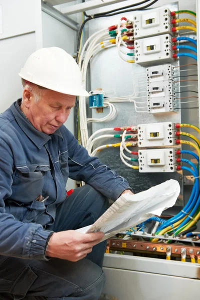 Eletricista na fiação com desenhos de trabalho — Fotografia de Stock
