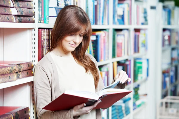 Jovem estudante menina leitura livro na biblioteca — Fotografia de Stock