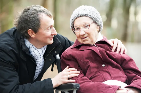 Stock image Old senior woman in wheelchair with careful son