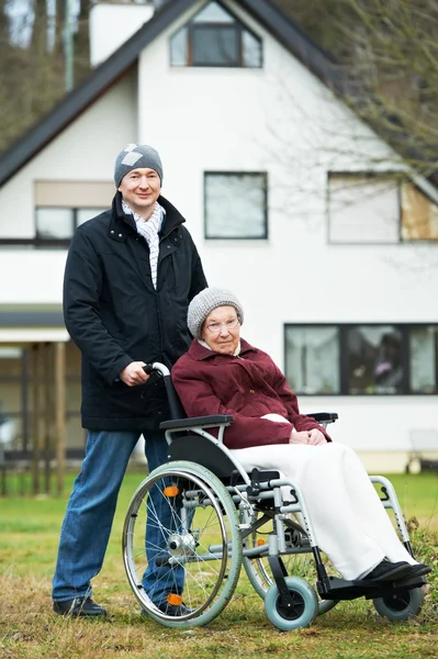 Old senior woman in wheelchair with careful son — Stock Photo, Image