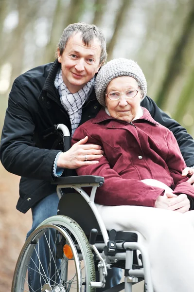 Äldre kvinna i rullstol med försiktig son — Stockfoto