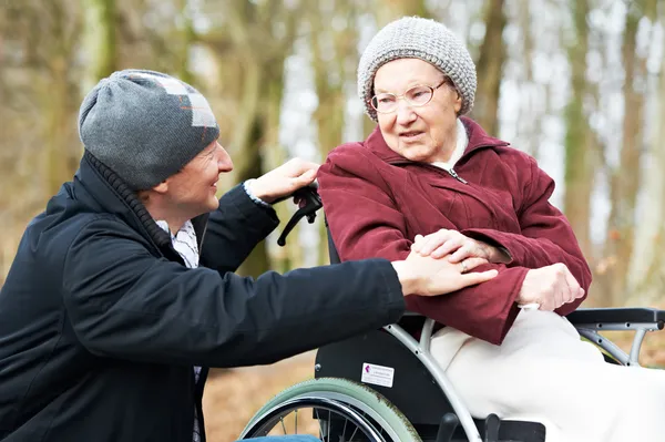 Alte Seniorin im Rollstuhl mit vorsichtigem Sohn — Stockfoto