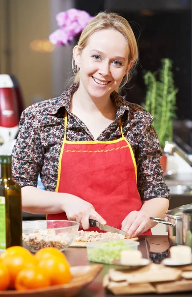 En smilende kvinne som lager mat på kjøkkenet sitt – stockfoto