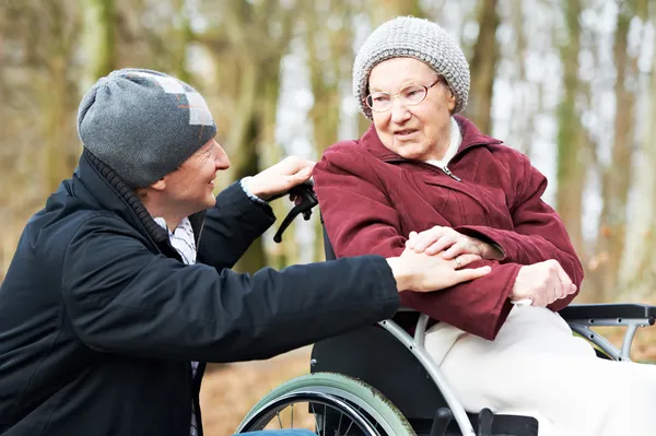 Äldre kvinna i rullstol med försiktig son — Stockfoto