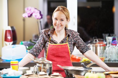 Smiling woman cooking in her kitchen clipart