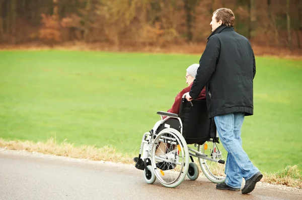 Vieja mujer mayor en silla de ruedas con hijo cuidadoso — Foto de Stock