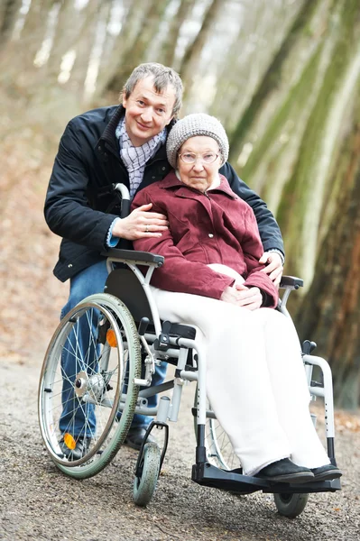 Стара старша жінка в інвалідному візку з ретельним сином — стокове фото