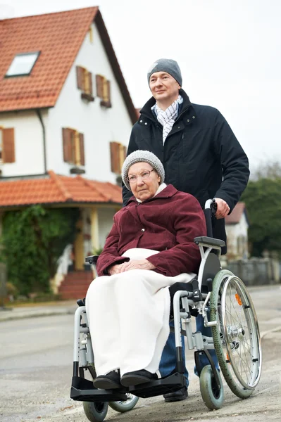 Vieja mujer mayor en silla de ruedas con hijo cuidadoso — Foto de Stock