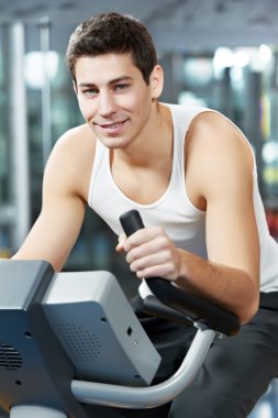 Positive man at legs bicycle exercises machine clipart