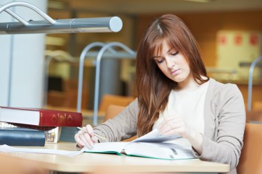 Young student girl study with book in library clipart