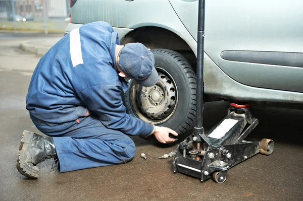 Reparador Machanic en el montaje de neumáticos con gato de coche —  Fotos de Stock
