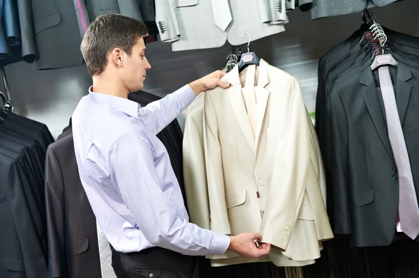 若い男が洋服店のスーツを選択します。 — ストック写真