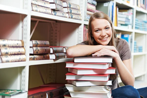Sorrindo jovem mulher adulta lendo livro na biblioteca — Fotografia de Stock