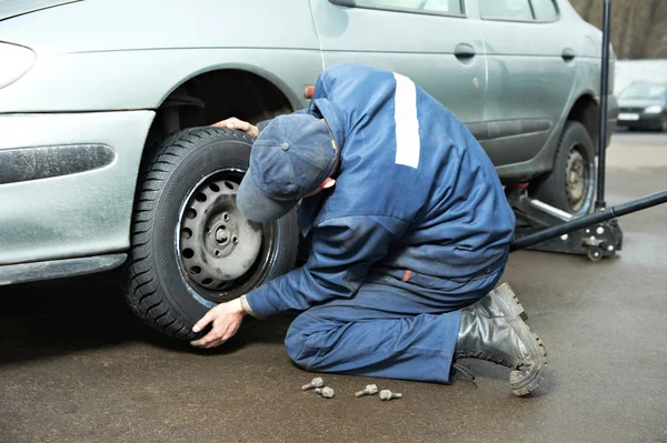 Reparador Machanic en el montaje de neumáticos con gato de coche — Foto de Stock