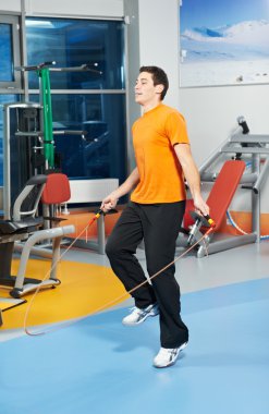 Positive man at legs exercises with skipping rope clipart