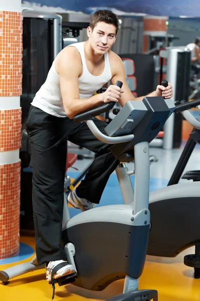 Positive man at legs bicycle exercises machine — Stock Photo, Image