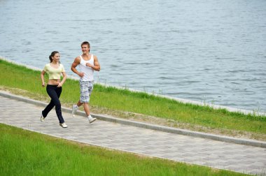 Young man and woman jogging outdoors clipart