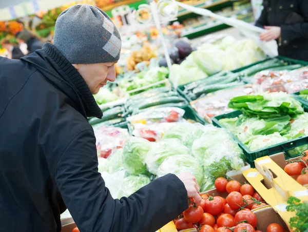 Mann wählt Gemüse im Supermarkt — Stockfoto
