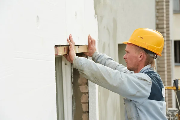 Construtor trabalhador de estucador de fachada com nível — Fotografia de Stock