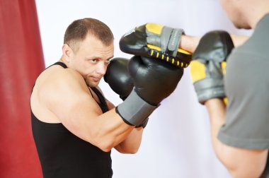 Boxer man at boxing training with punch mitts clipart