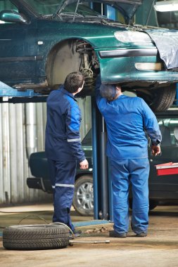 Two car mechanic diagnosing auto suspension clipart